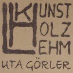 Sgraffito-Logo „Kunst Holz Lehm“ in dunklem Lehmputz